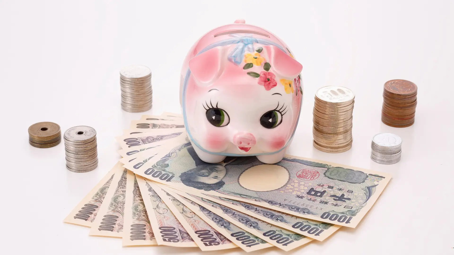 Piggy bank on a desk with coins and cash around it, symbolizing the psychology of money habits, mindful saving, and the 7 key habits that separate savers from spenders.